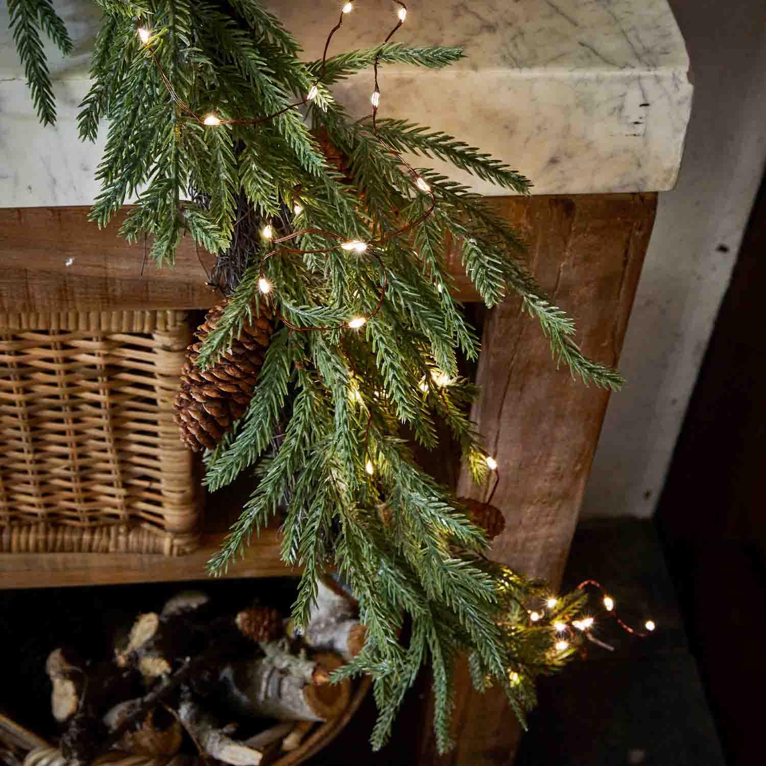 Sparrentak met dennenappel en LED-lichtjes aan houten open haard, feestelijke kerstdecoratie