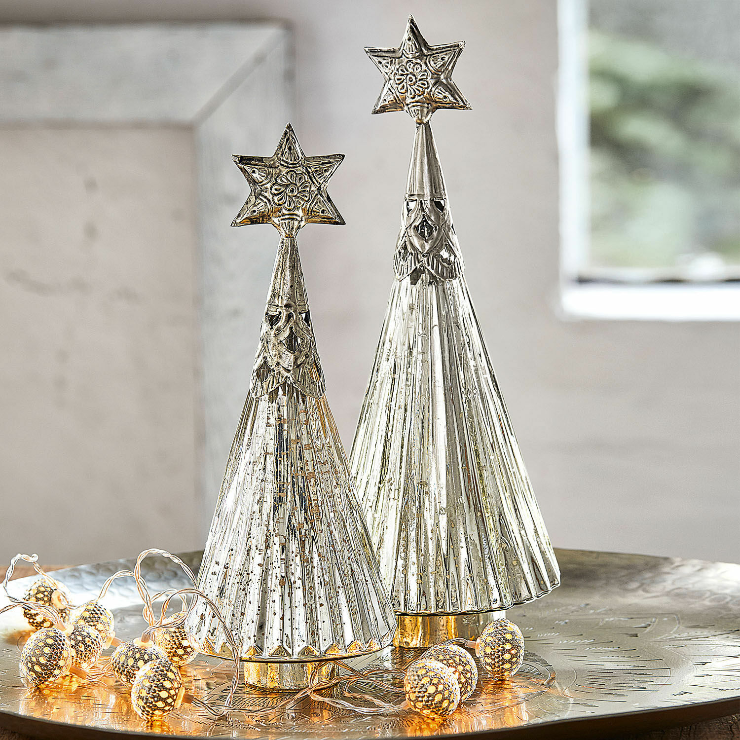 Sierkerstboom set van 2 Lillemor Twee zilverkleurige metalen kerstbomen met sterren bovenop op feestelijke tafel met LED-lichtjes