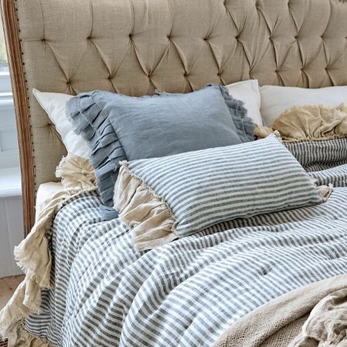 Beige en blauwe linnen kussens met gestreept linnen dekbed op een gestoffeerd hoofdeinde