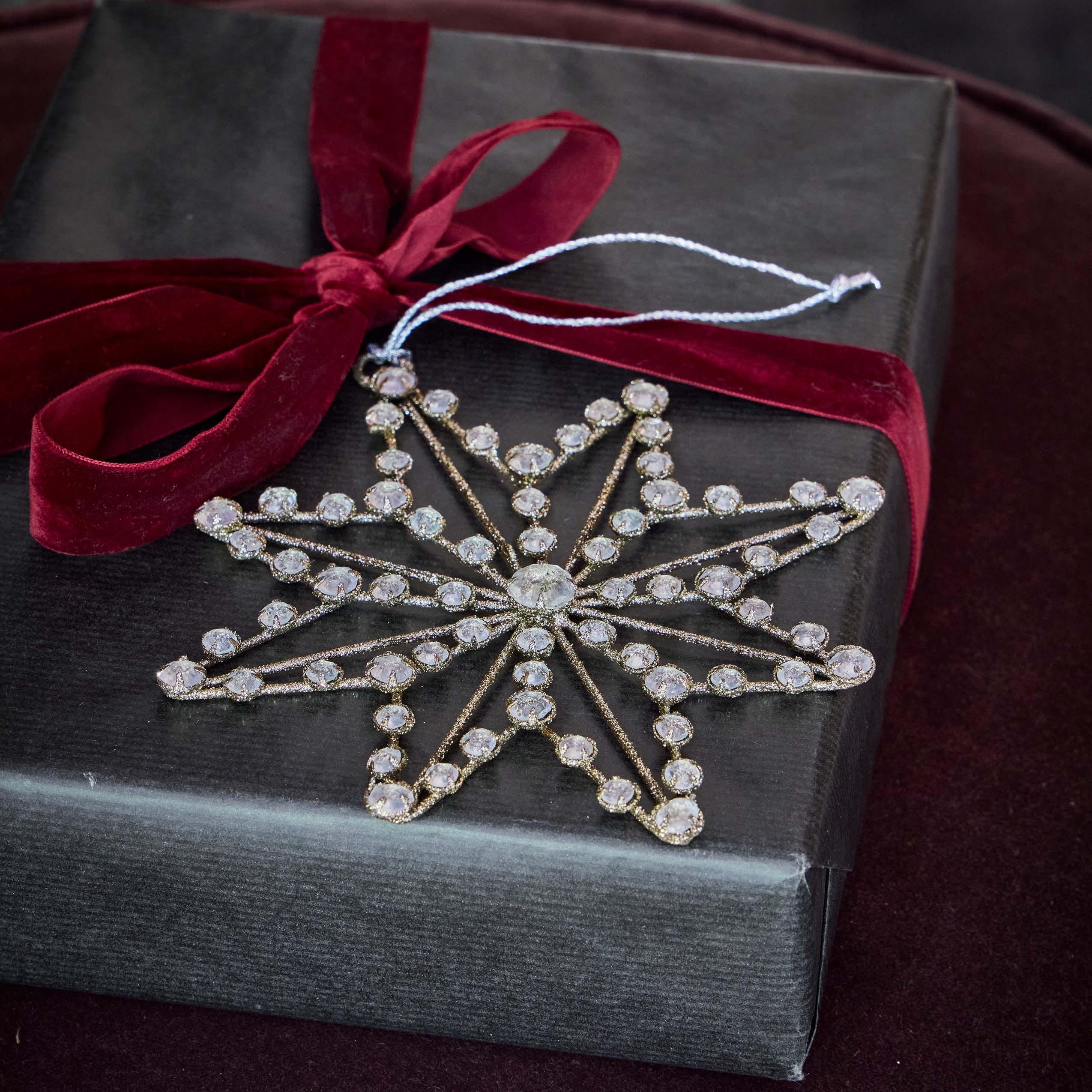 Kerststerdecoratie met kristallen op zwarte achtergrond en bordeauxrode fluwelen strik
