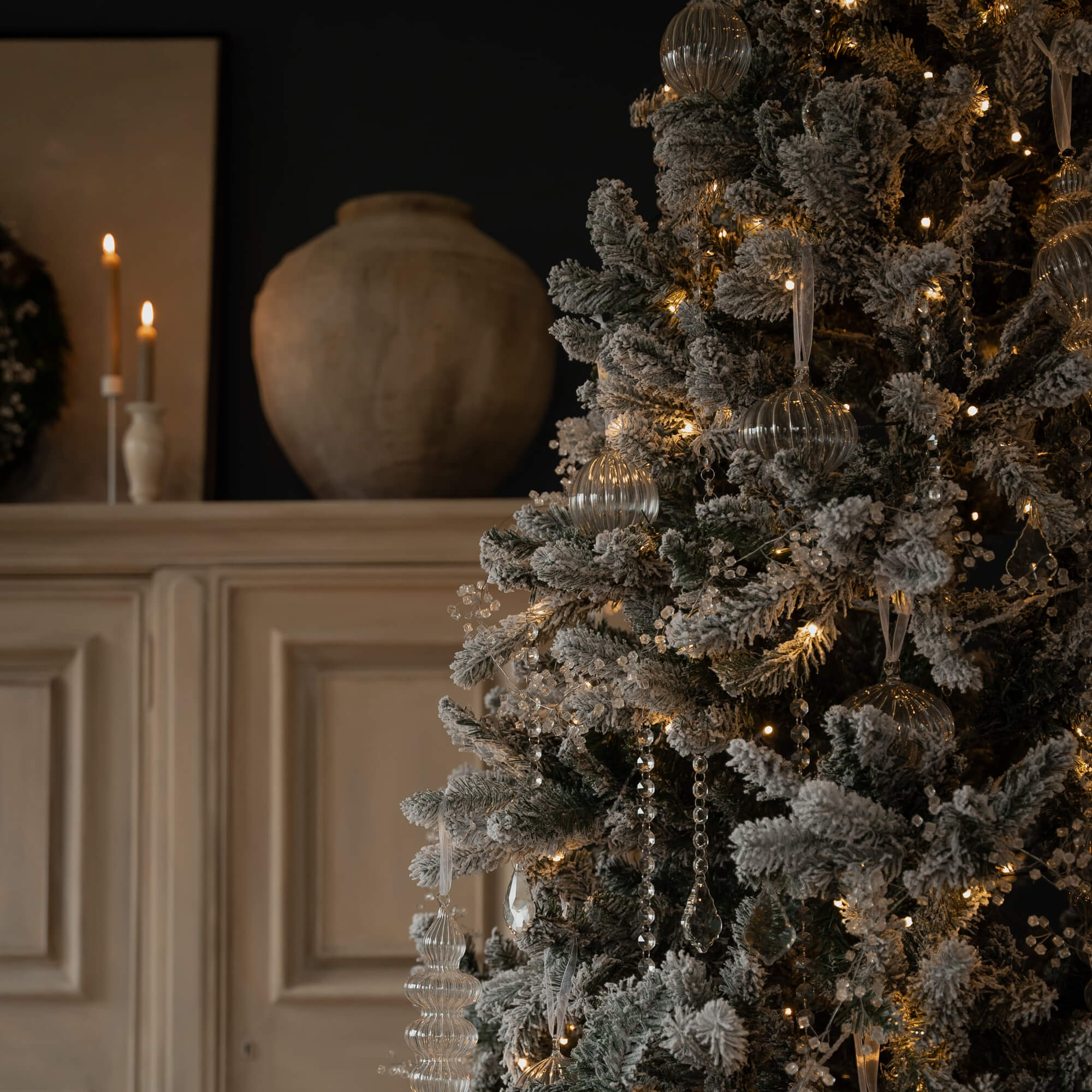 Kunstkerstboom met witte sneeuwlook en glazen ornamenten, versierd met LED-lichtjes voor kerst