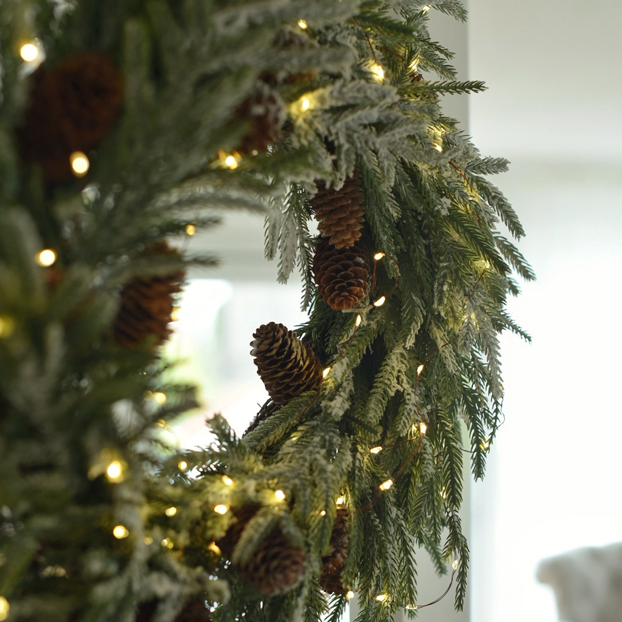 Kerstkrans van groene takken met dennenappels en warme LED-verlichting als winterdecoratie