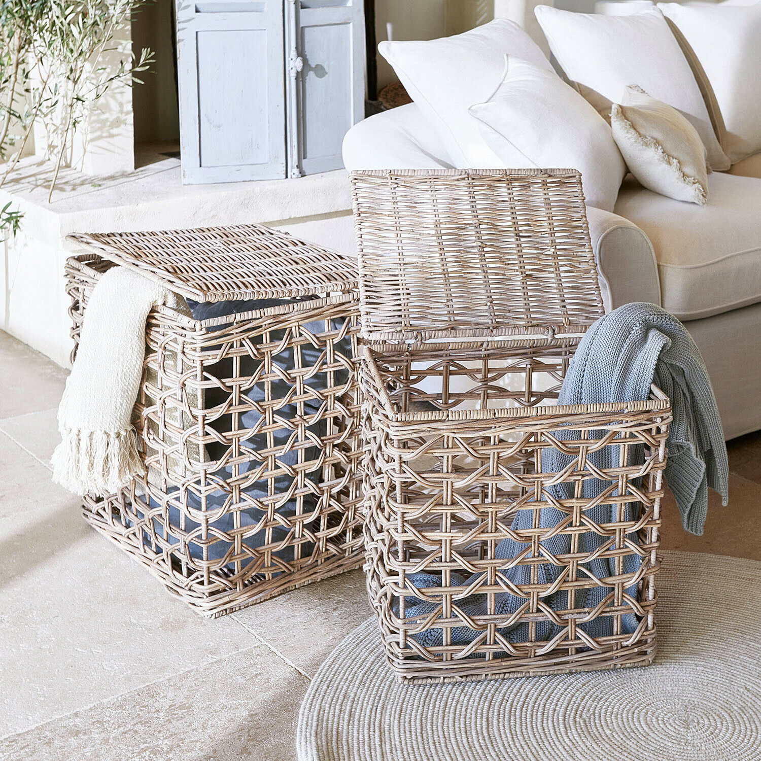 Twee natuurlijke rieten wasmanden met dekens, praktische opbergoplossing in lichte woonkamer
