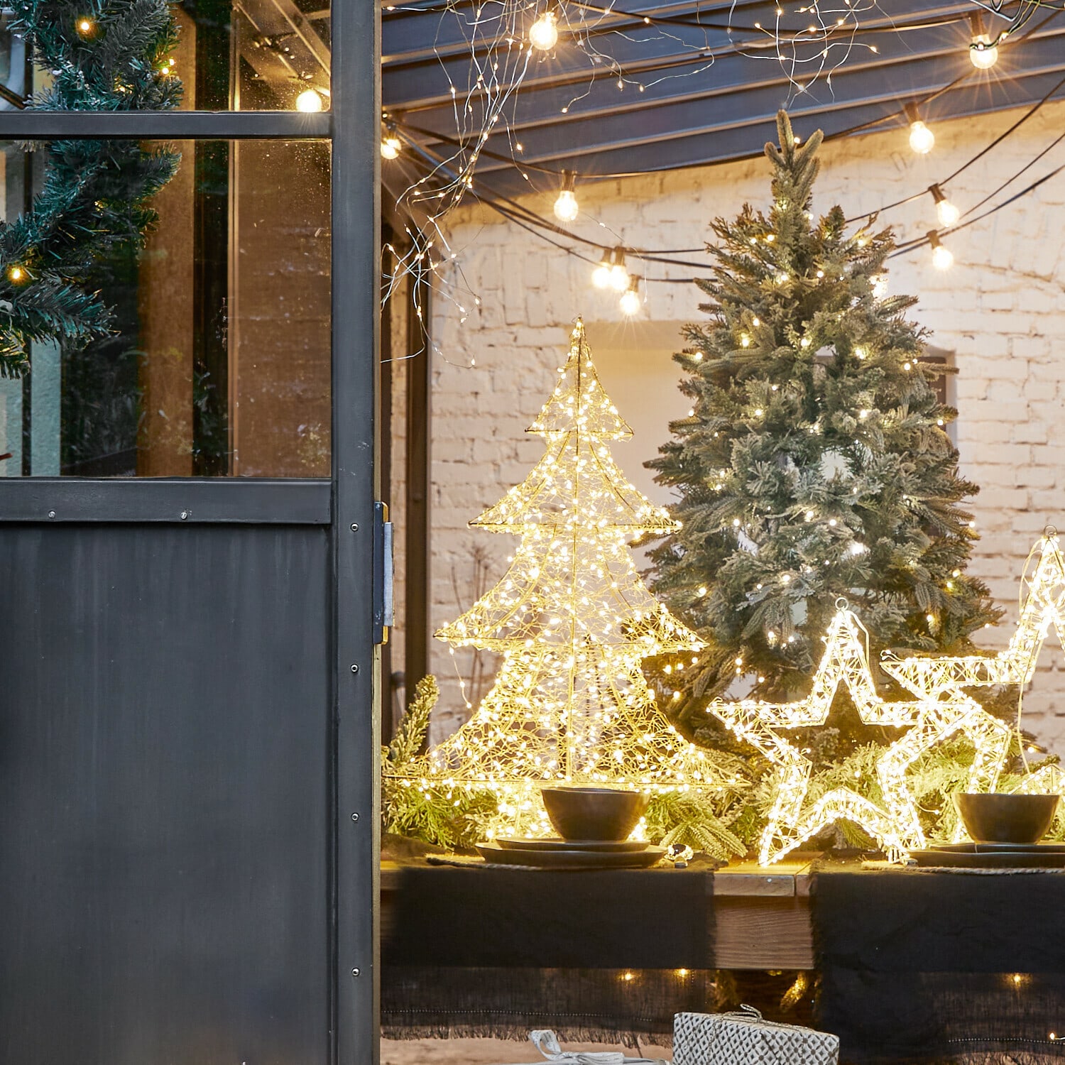 Boom met LED-lampjes Vivetelle LED-kerstdecoraties in de vorm van boom en ster op houten tafel met groene takken