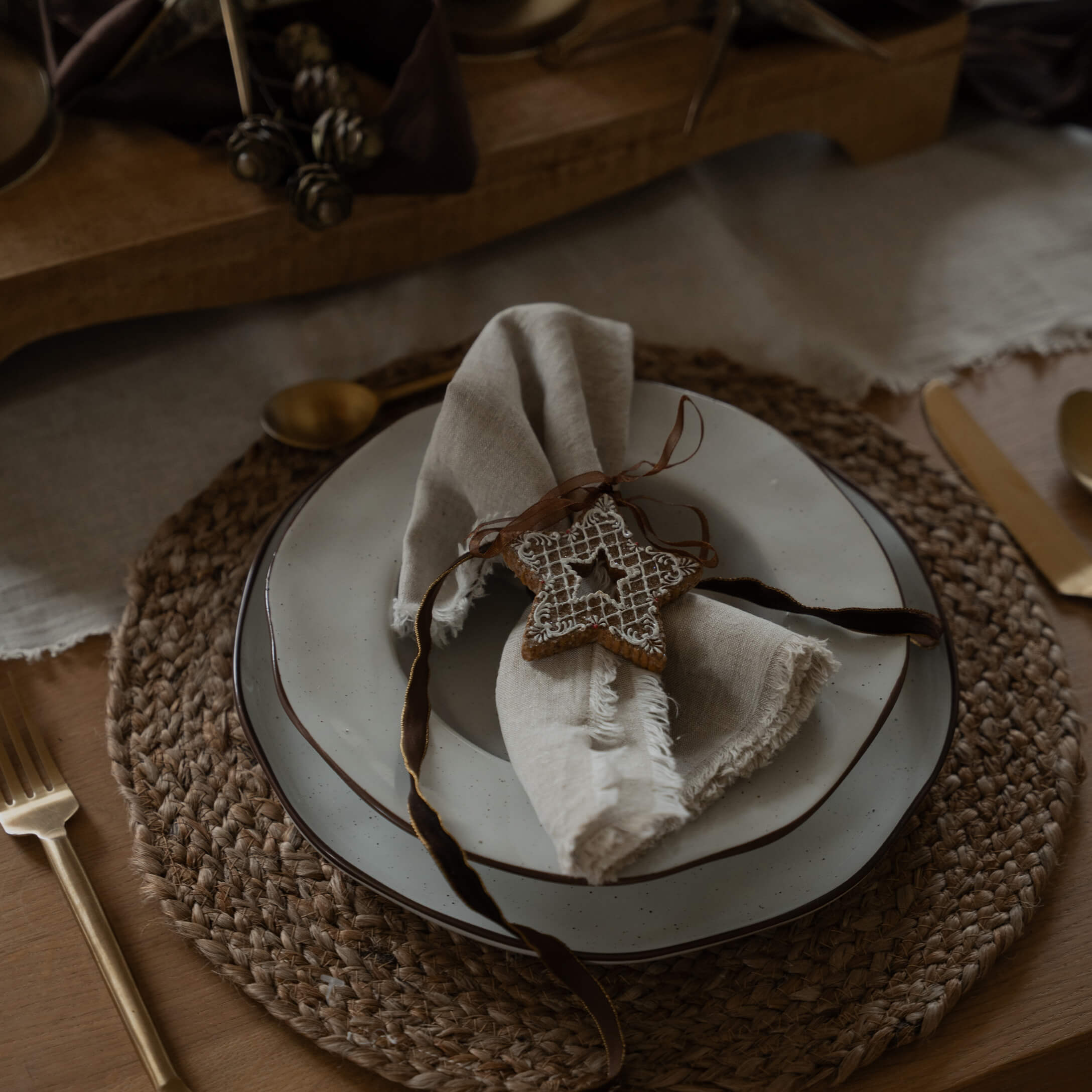 Rustieke tafel met gevlochten placemat, wit bord en linnen servet met sterversiering