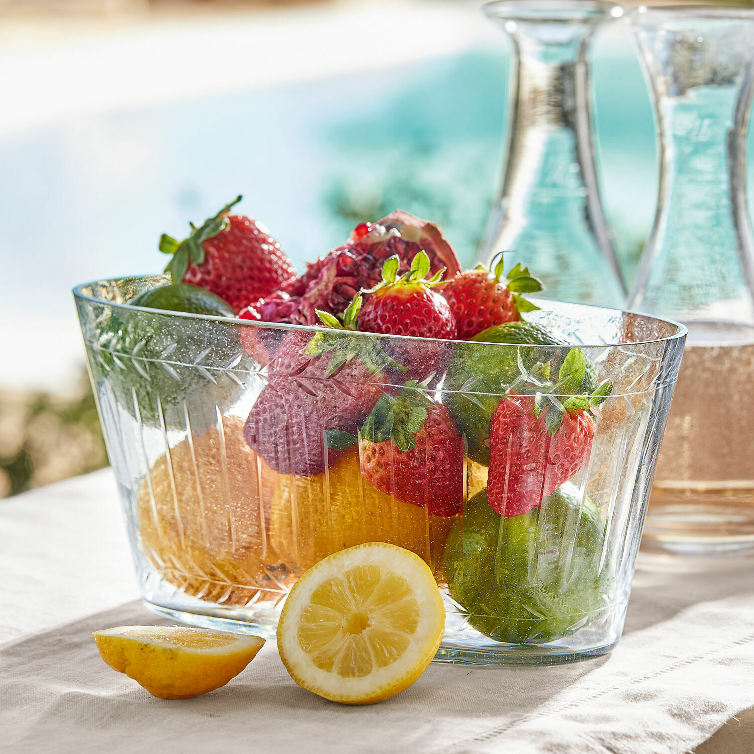 Schaal Malinda Transparante glazen schaal met aardbeien, limoenen en citroen op lichte tafelkleed, tafeldecoratie