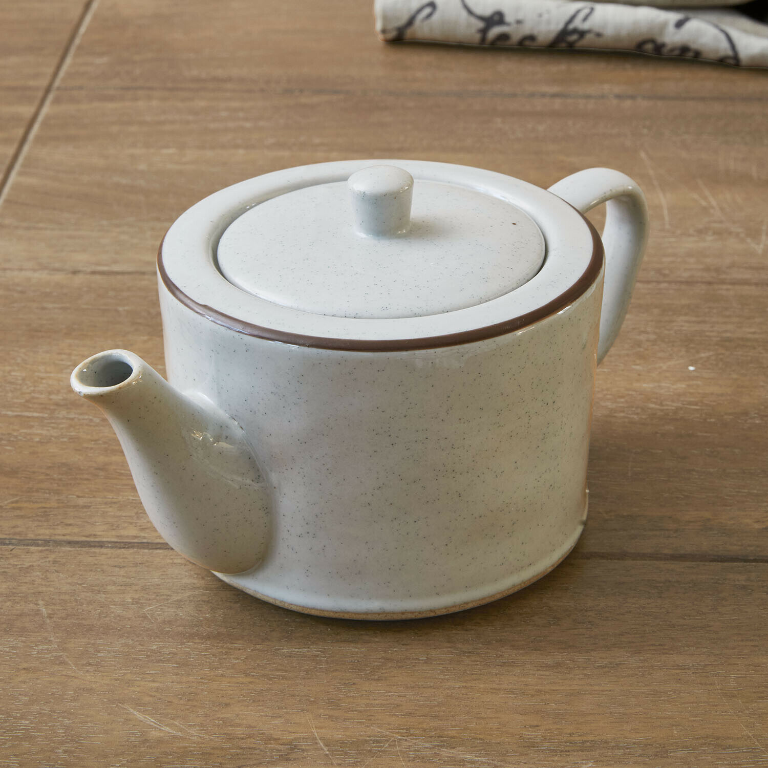 Witte keramische theepot met bruine rand op houten tafel voor het zetten van thee
