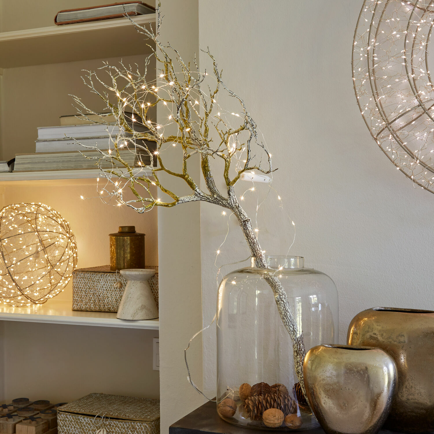 Decoratieve tak met LED-lichtjes in een doorzichtige glazen vaas met noten en dennenappels