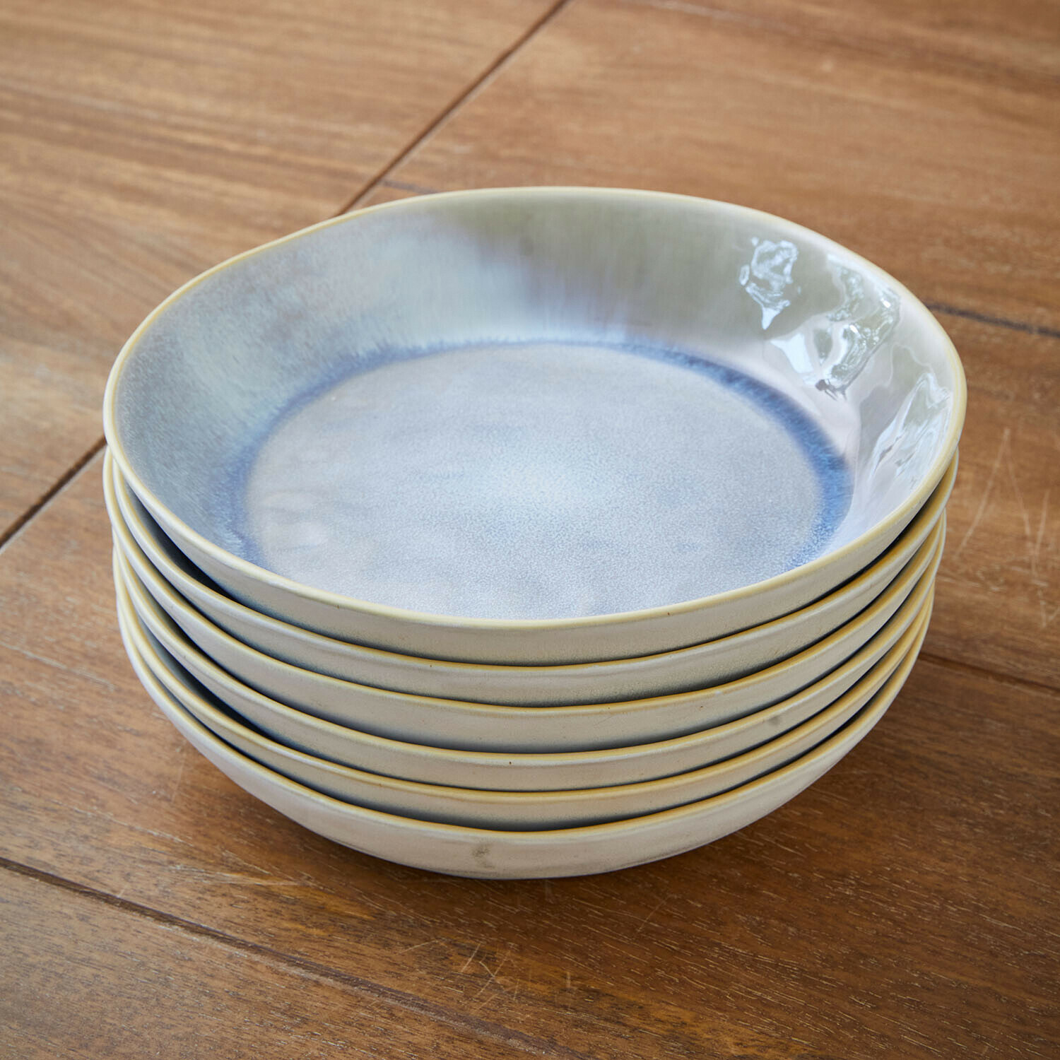 Set van zes keramische borden in blauw en beige tinten op houten tafel gestapeld