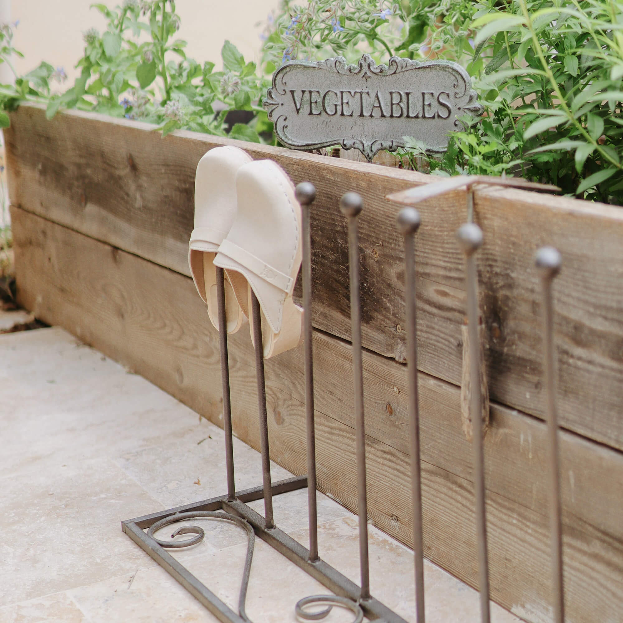 Metalen schoenenrek met witte leren slippers voor houten plantenbak met kruiden