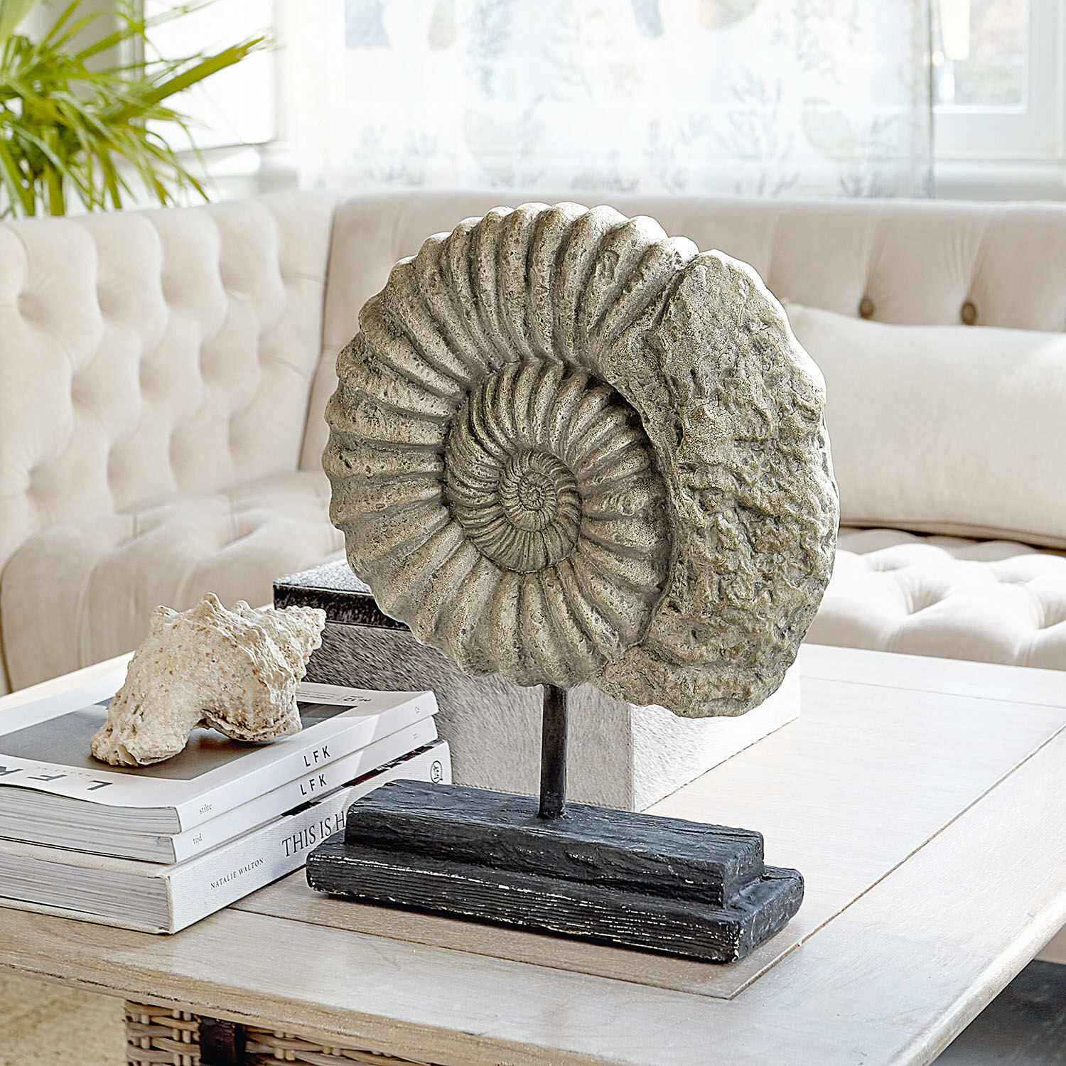 Decoratief ammonietbeeld van steen op zwarte voet op salontafel in woonkamer
