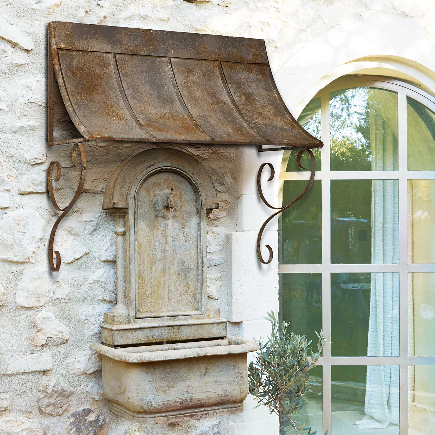 Rustieke stenen wandfontein met roestig metalen luifel, geschikt voor tuindecoratie