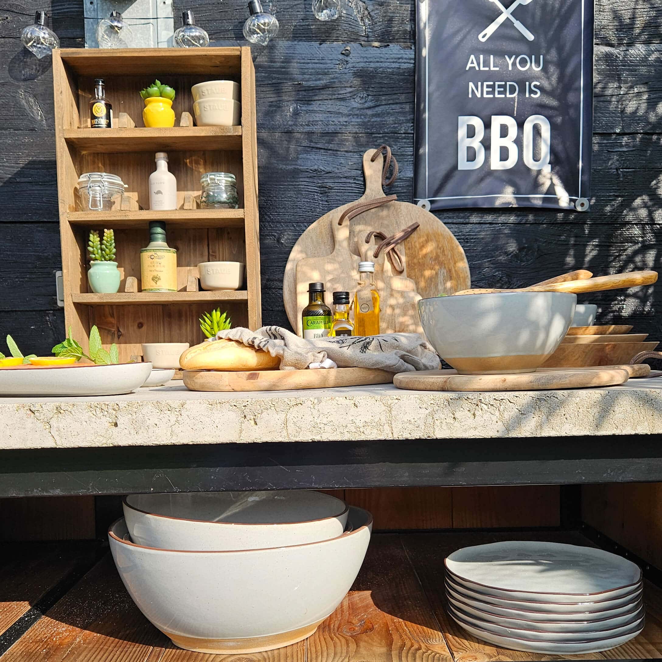 Set beige keramische kommen en borden met houten snijplanken en olieflesjes op een barbecue tafel