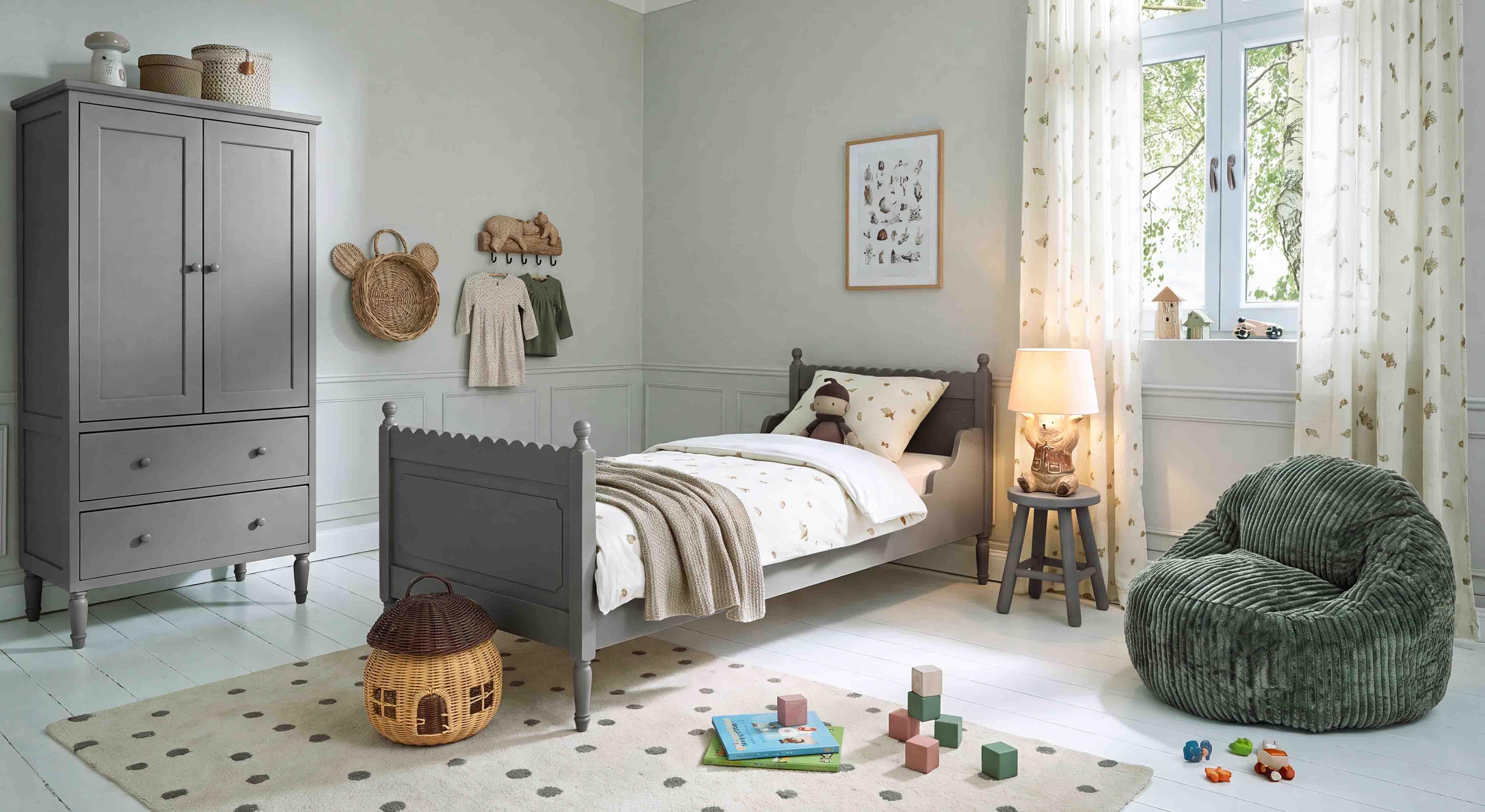 Grijze houten kast en bed in kinderkamer met zachte groene fauteuil en decoraties