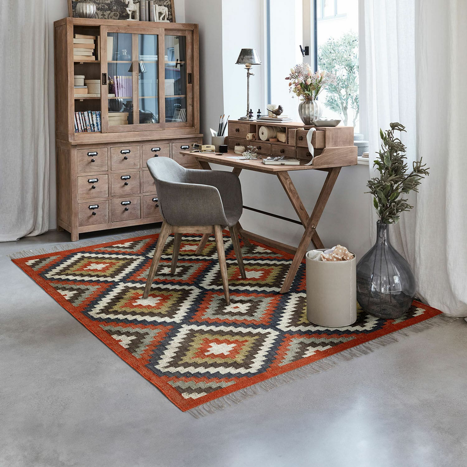 Vloerkleed Dailies Vloerkleed met geometrisch patroon in warme kleuren in modern kantoor met houten bureau en grijze stoel