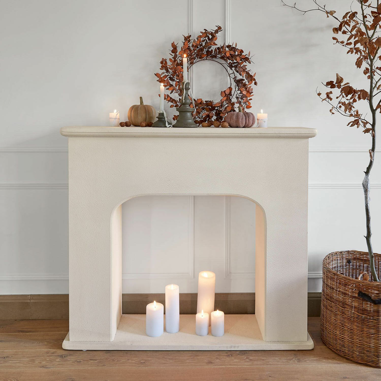 Decoratieve witte schouw van gestructureerd materiaal met brandende kaarsen en herfstdecoratie