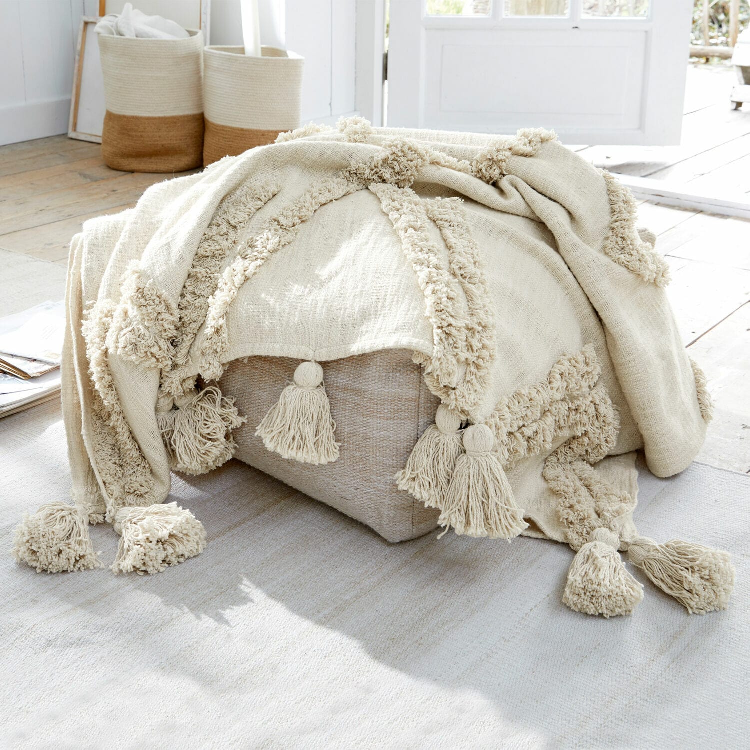 Plaid Linares Beige katoenen deken met kwastjes op lichte poef in natuurlijk lichte kamer