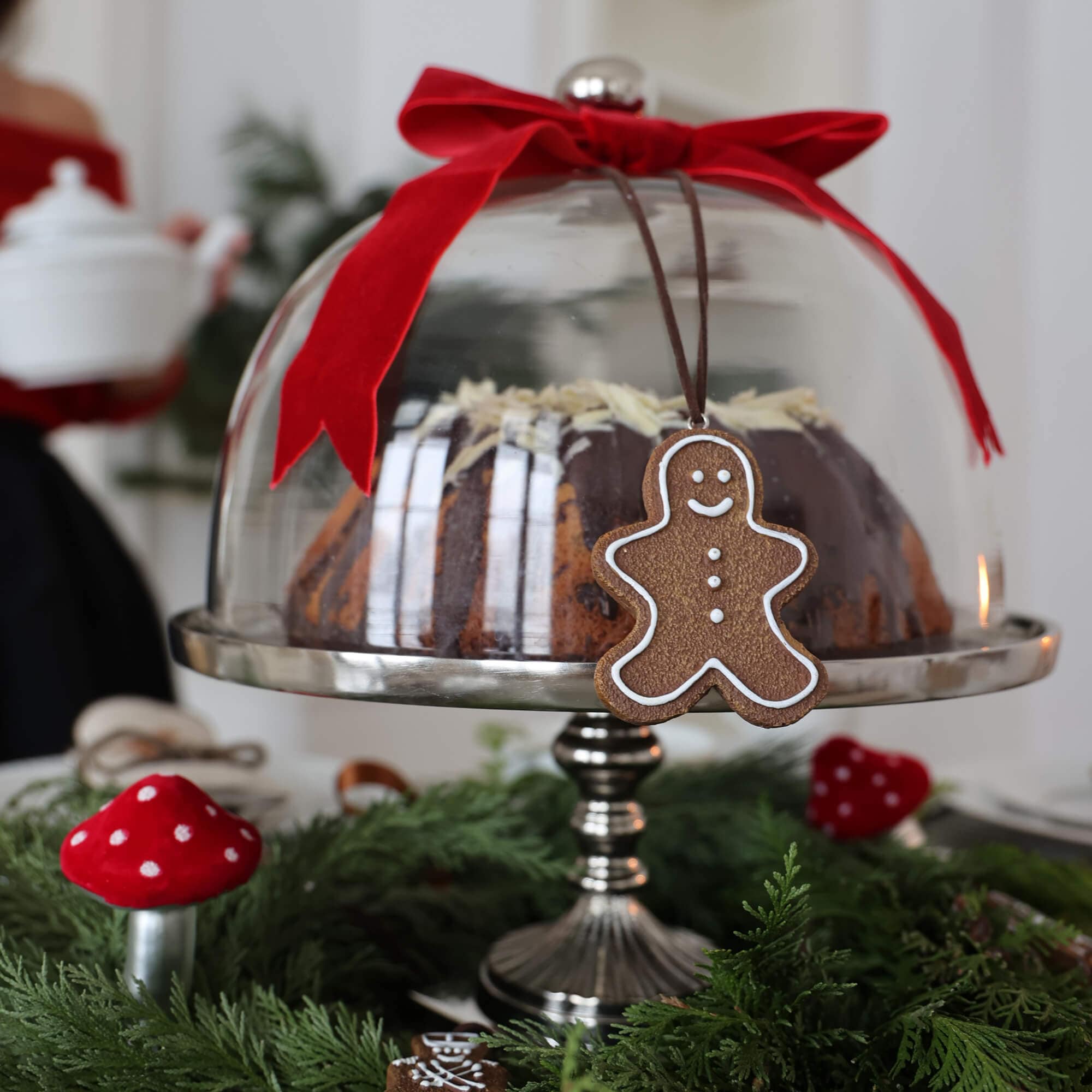 Glazen stolp met rode strik en peperkoekmannetje hanger op feestelijke tafel