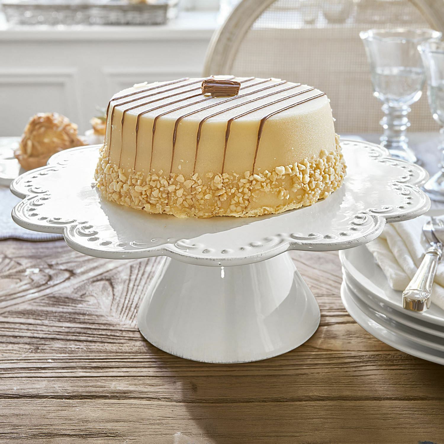 Witte keramische taartstandaard met decoratieve rand op houten tafel in eetkamer