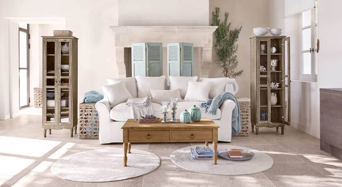 Gezellige witte katoenen bank in maritieme stijl met houten salontafel en decoraties in lichte kamer