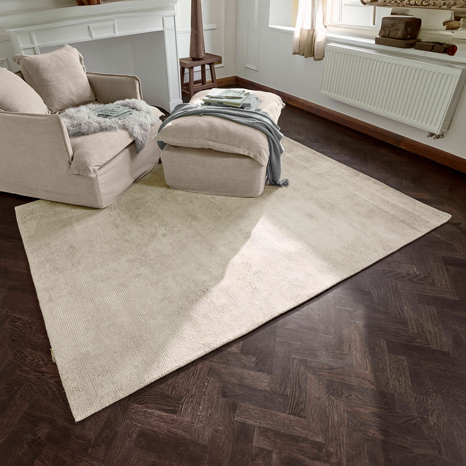 Beige vloerkleed van zacht materiaal op donkere houten vloer in gezellige woonkamer