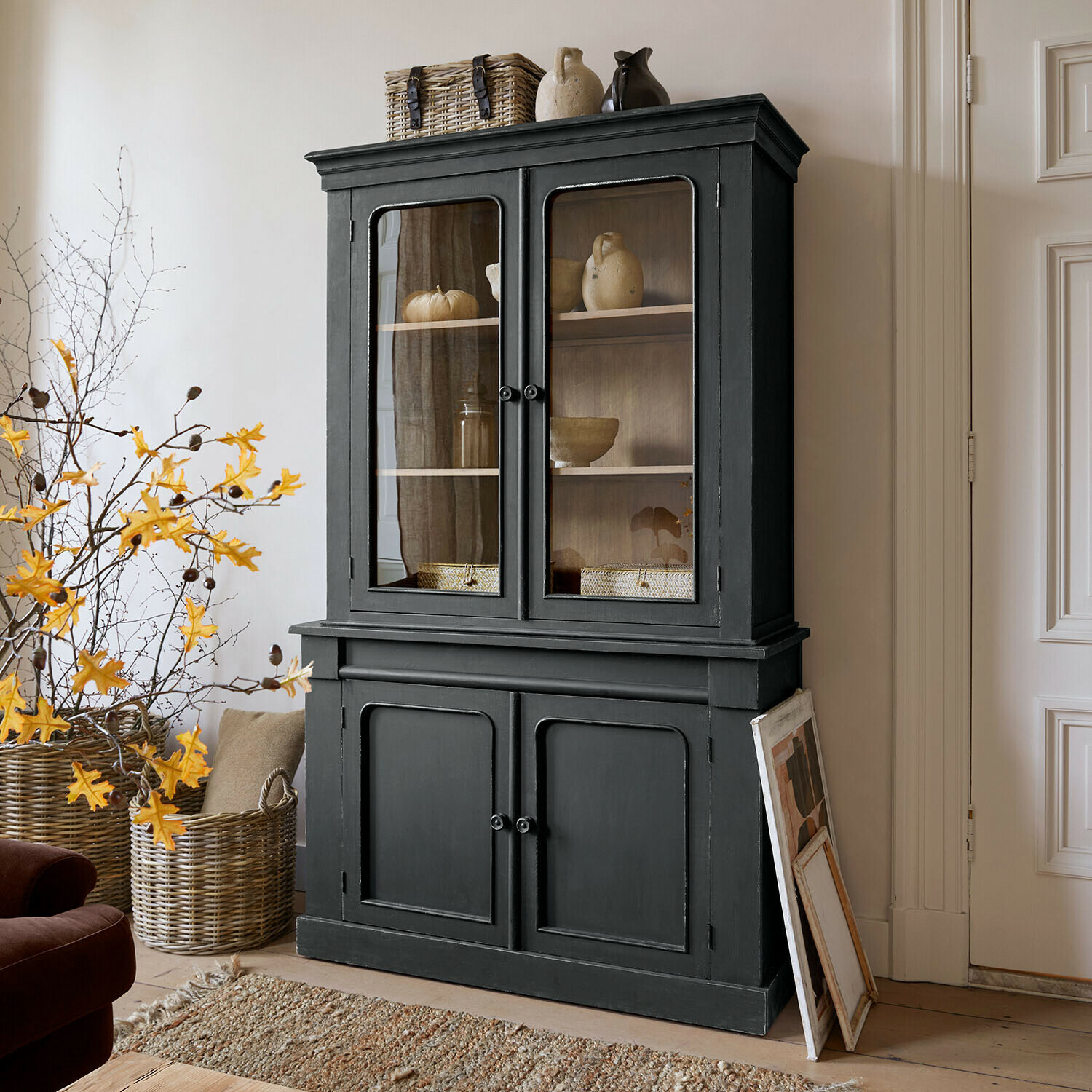 Kast Aldwyn Zwarte houten vitrinekast met glazen deuren en keramische decoraties in woonkamer
