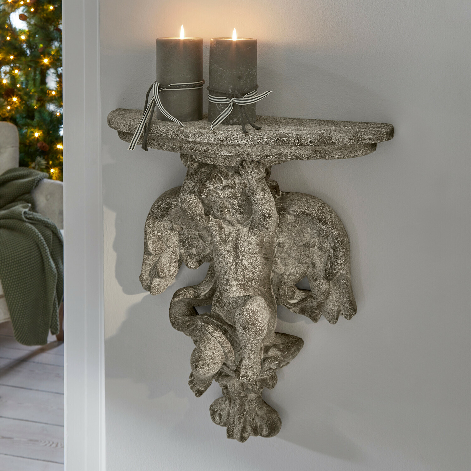 Wandconsole van grijs steen met engel en twee grijze kaarsen, interieurdecoratie