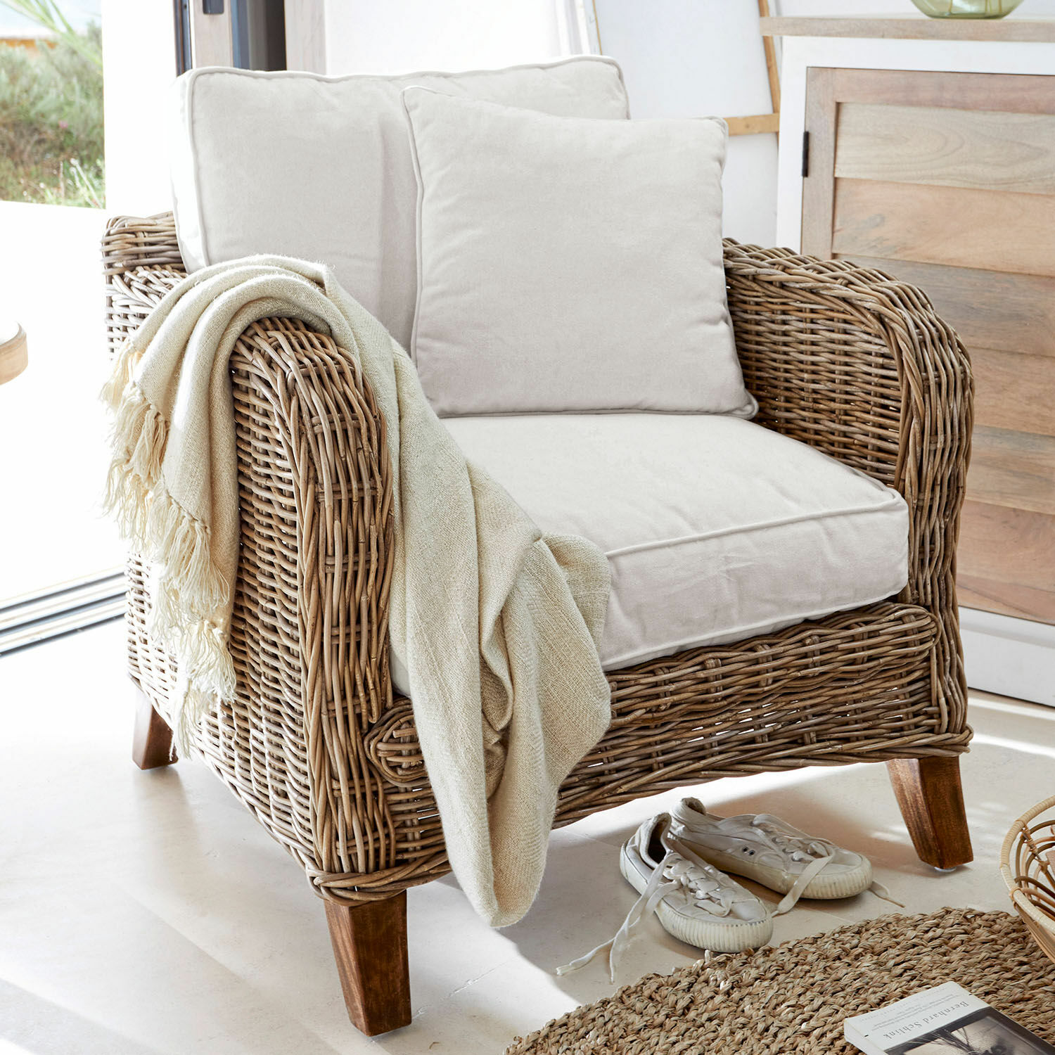 Fauteuil Colroy Rotan fauteuil met crèmekleurige kussens en beige deken, natuurlijke interieurstijl, rotan meubels