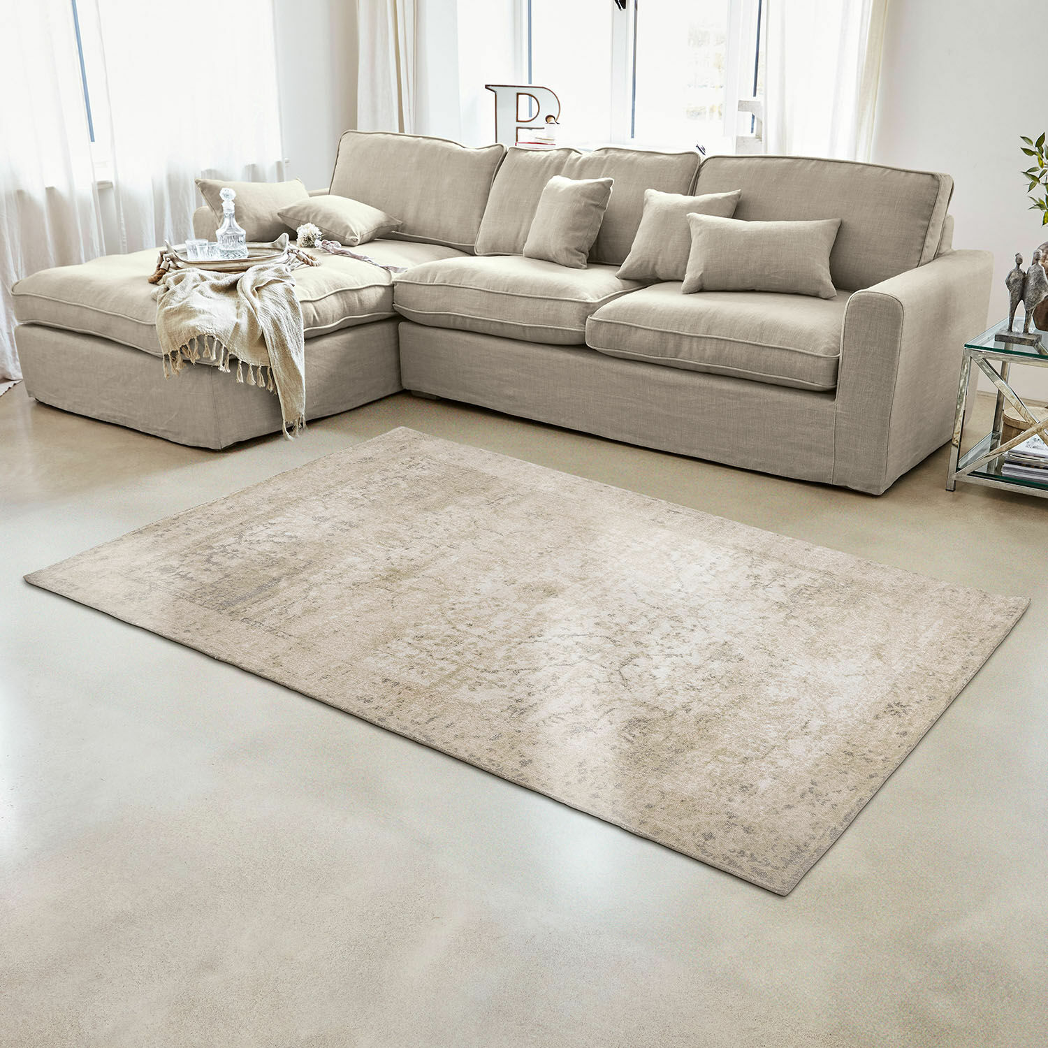 Beige vloerkleed met subtiel patroon op lichte vloer in moderne woonkamer met bank