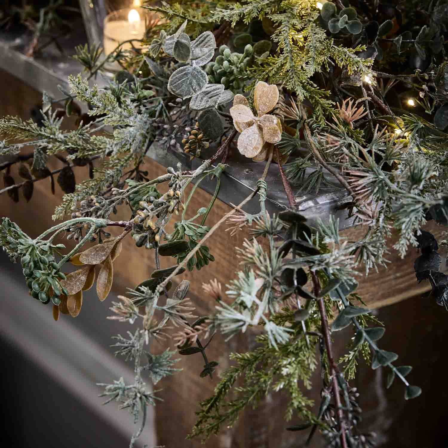 Decoratieve krans van groene en beige takken met zachte LED-verlichting op houten achtergrond
