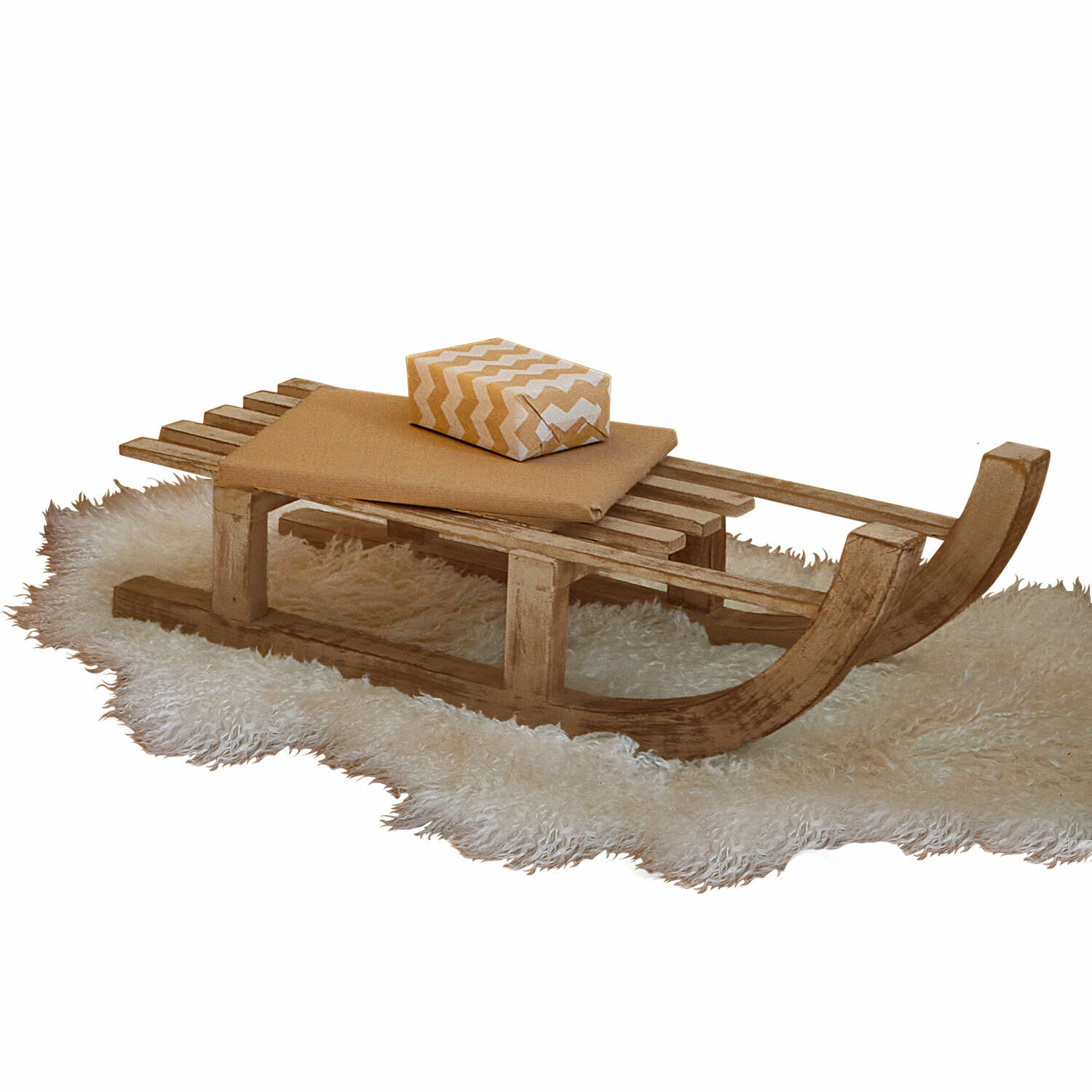 Houten slee op witte bontachtige mat met beige kussen en cadeau in zigzagpatroon