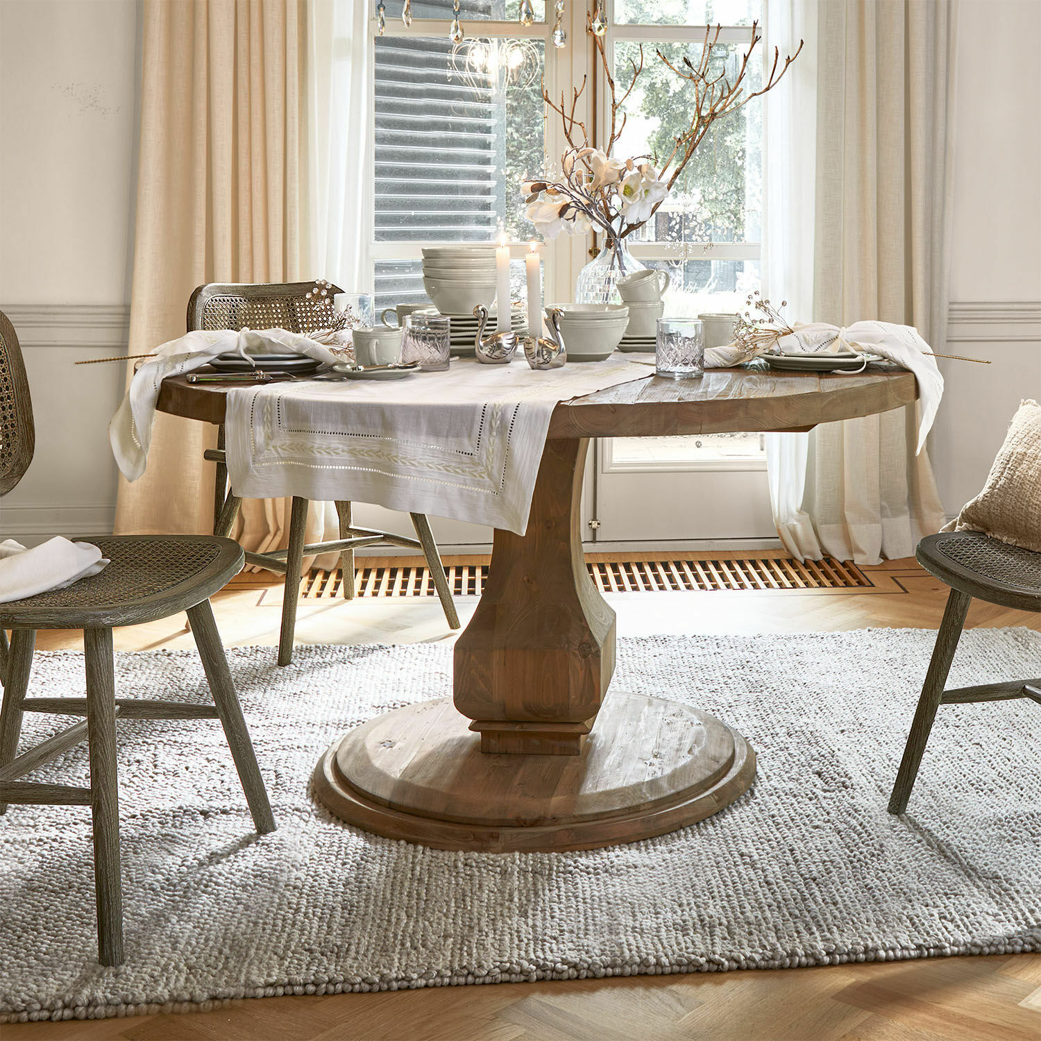 Tafel Alderwick Ronde houten tafel met wit tafelkleed en decoratie in lichte, gezellige eetkamer met natuurlijk licht