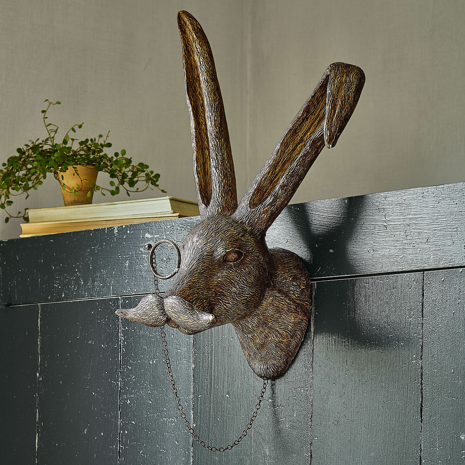 Decoratief konijnenhoofd van bruin metaal met snor en monocle aan de muur