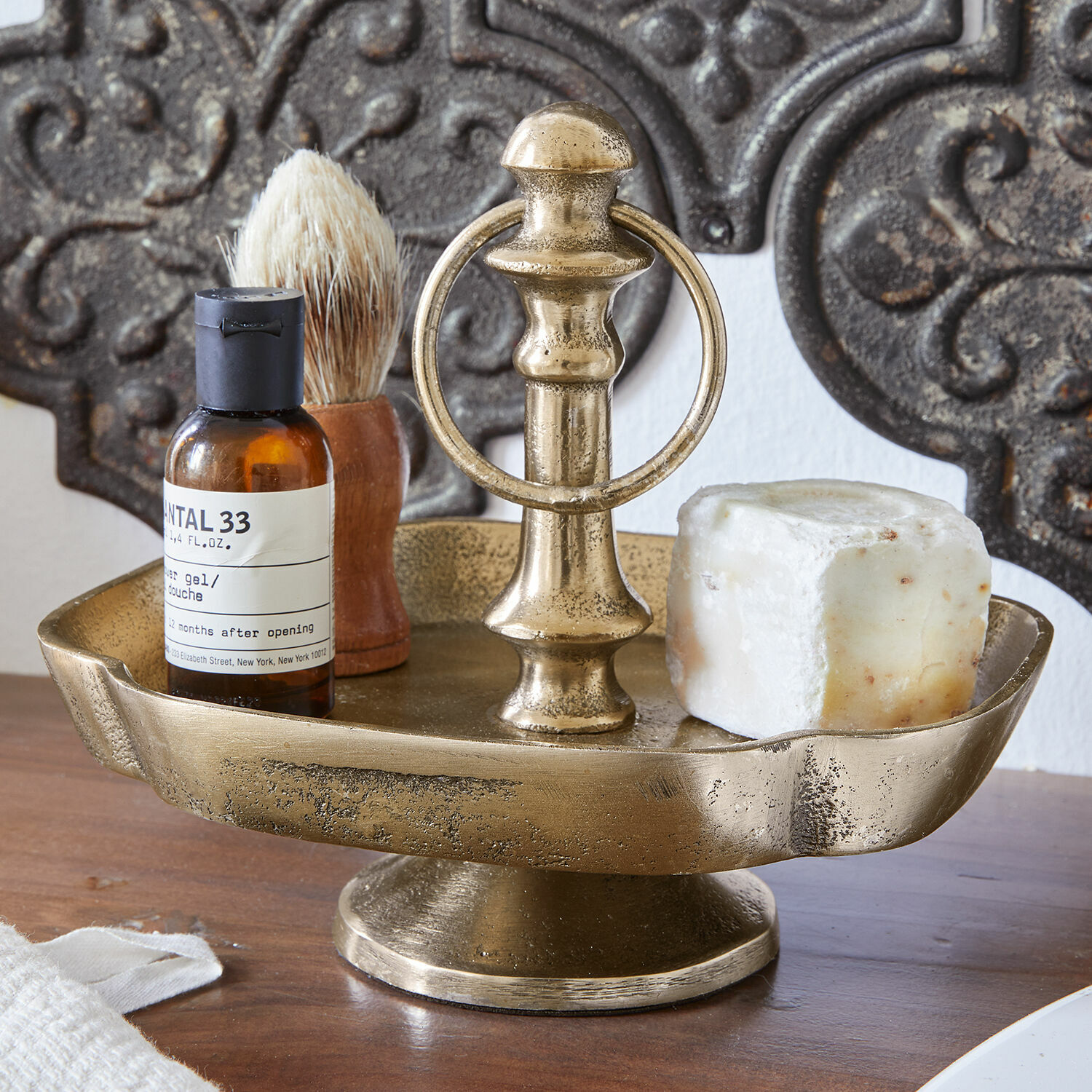 Gouden metalen zeepschaal met handvat, zeep en scheeraccessoires op houten oppervlak