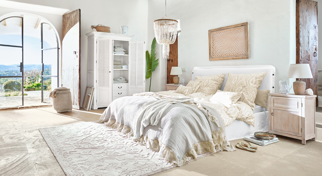 Lichte slaapkamer met wit bed, beige beddengoed en rustieke houten meubels