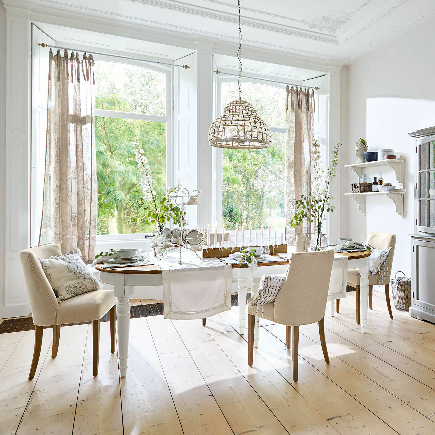 Eettafel Pinecrest Eetkamer met witte houten tafel en beige stoelen op lichte houten vloer, decoraties en hanglamp van riet