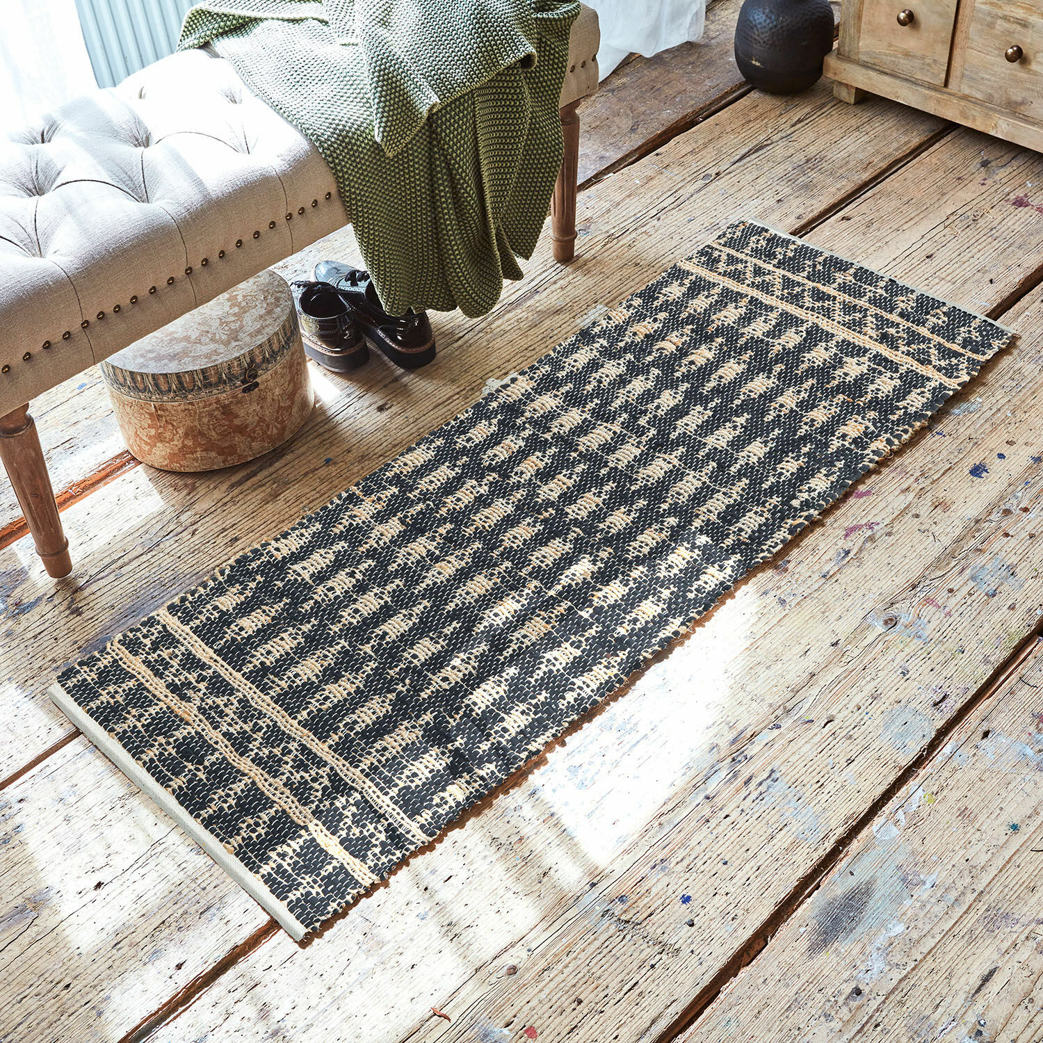 Zwart-beige vloerkleed van natuurlijk materiaal op houten vloer in gezellige ruimte