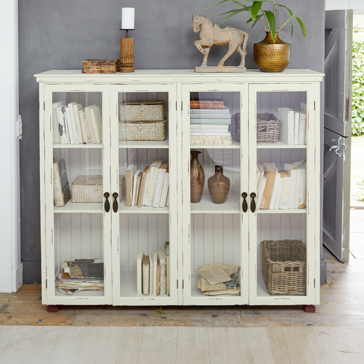 Kast Eastbridge Witte houten vitrinekast met glazen deuren, versierd met boeken en vintage decoraties in landelijke stijl