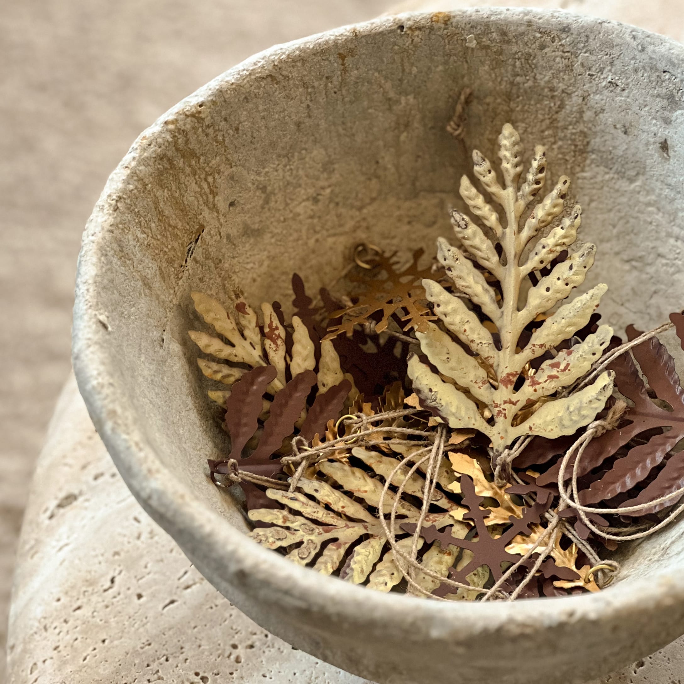 Decoratieve metalen bladeren in beige stenen kom, natuurlijke kleuren voor interieurdecoratie