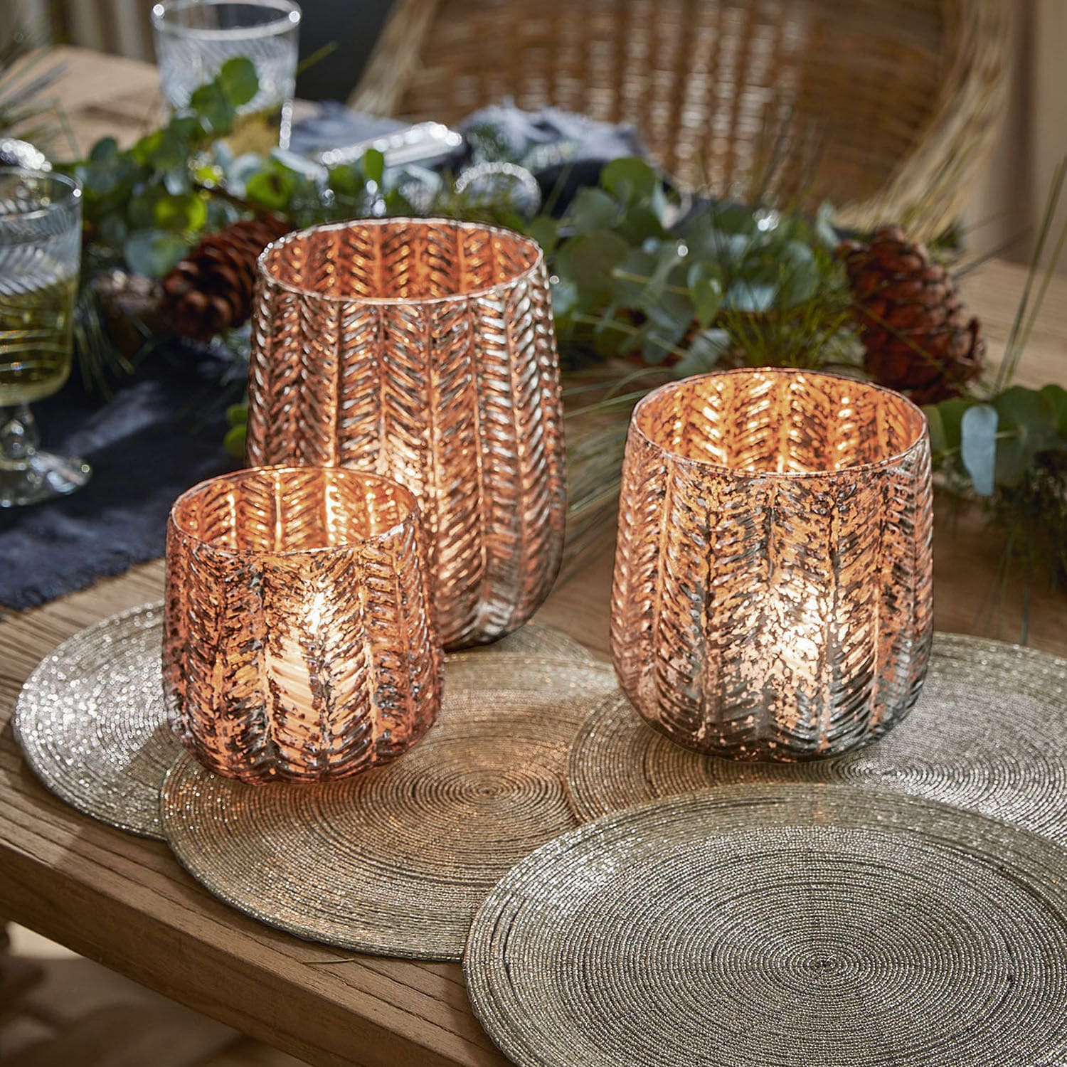 Windlicht set van 3 Centrès Set van drie koperen glazen windlichten met bladmotief op houten tafel met feestelijke decoratie