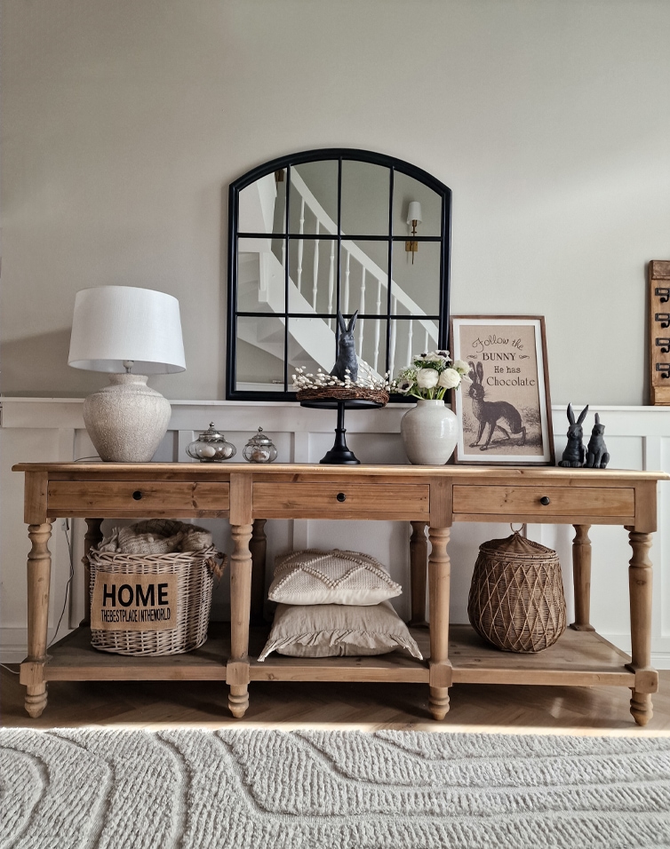 Houten tafel met rustieke decoraties, zwarte spiegel en tafellamp in een gezellige kamer