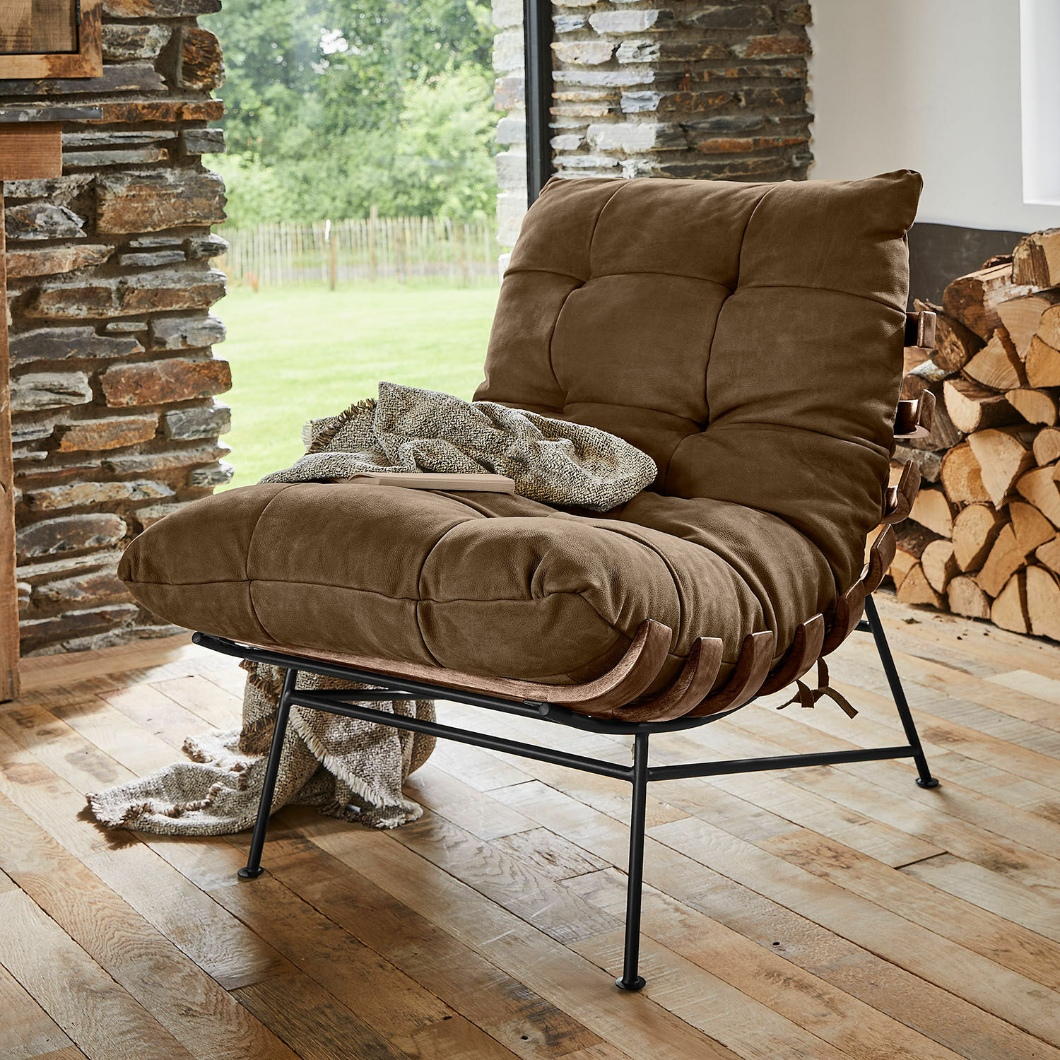 Fauteuil Horraine Bruine stoel met zachte bekleding en metalen frame op houten vloer in een gezellige ruimte