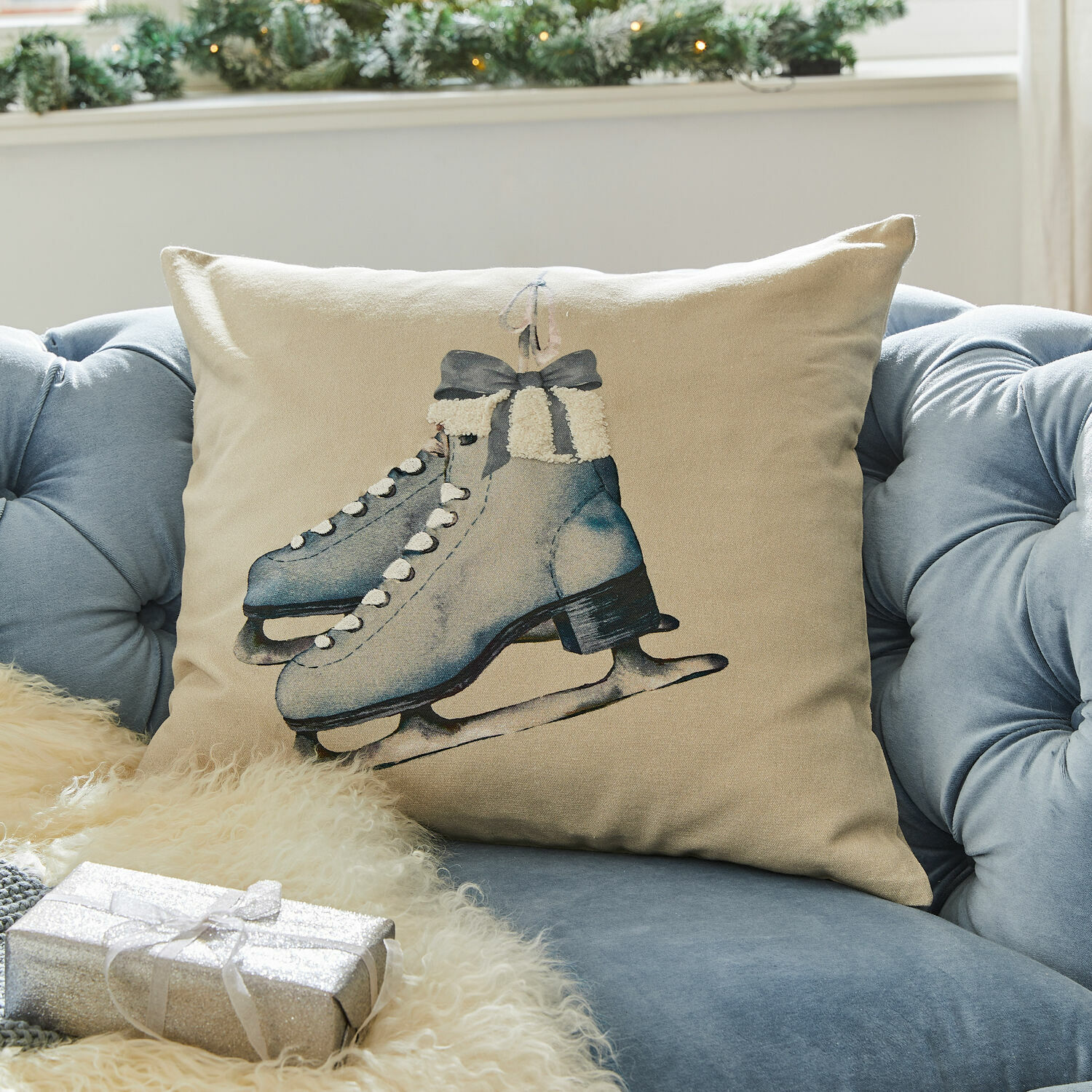 Beige kussen met blauwe schaatsenprint op blauwe bank, winterse en feestelijke decoratie
