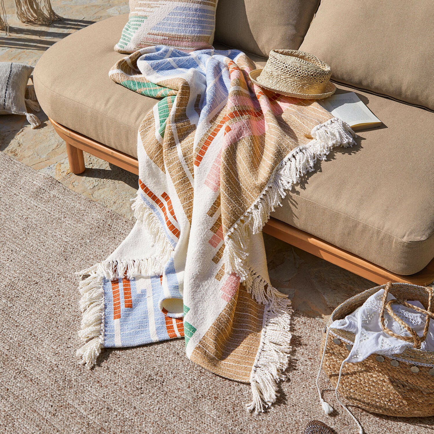 Plaid Amapina Kleurrijk katoenen deken met franjes op beige bank buiten, decoratief en comfortabel