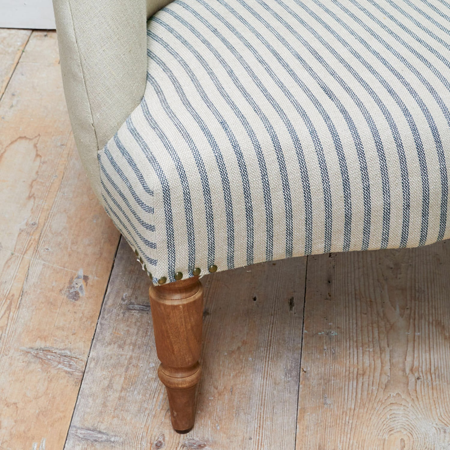 Houten meubelpoot met beige-blauw gestreepte bekleding op een houten vloer