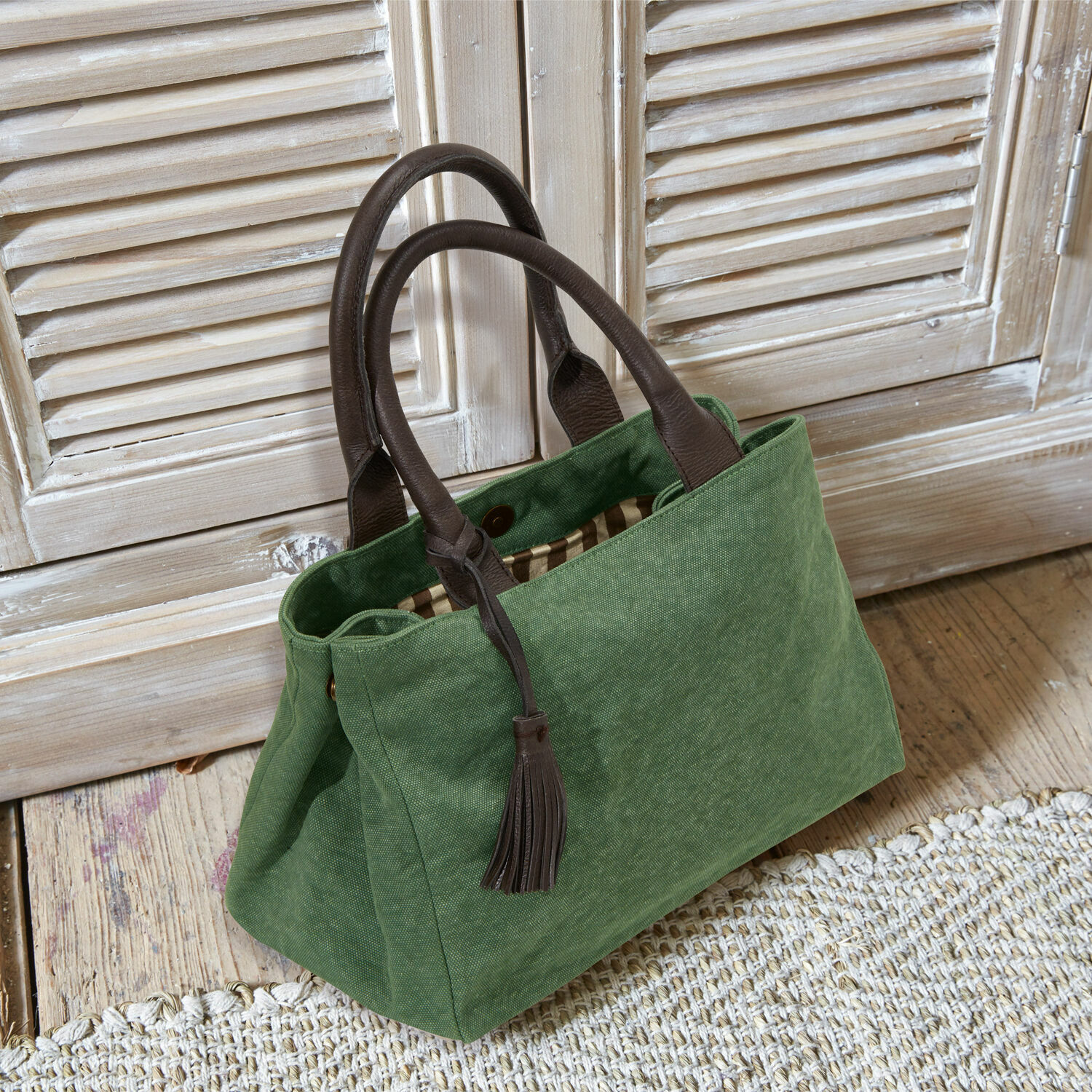 Tas Hoya Groene stoffen tas met bruine leren handvatten en kwast op lichte houten vloer