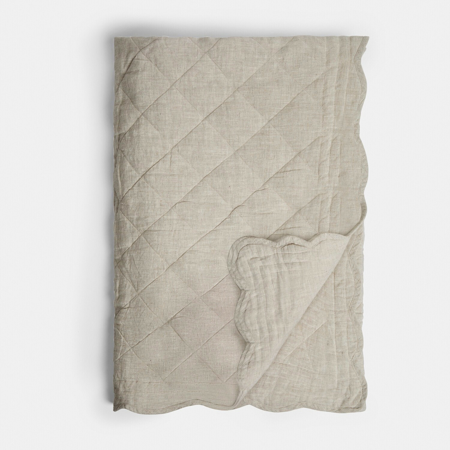 Beige doorgestikte linnen deken met decoratieve golvende rand, zachte natuurlijke stof voor slaapkamer