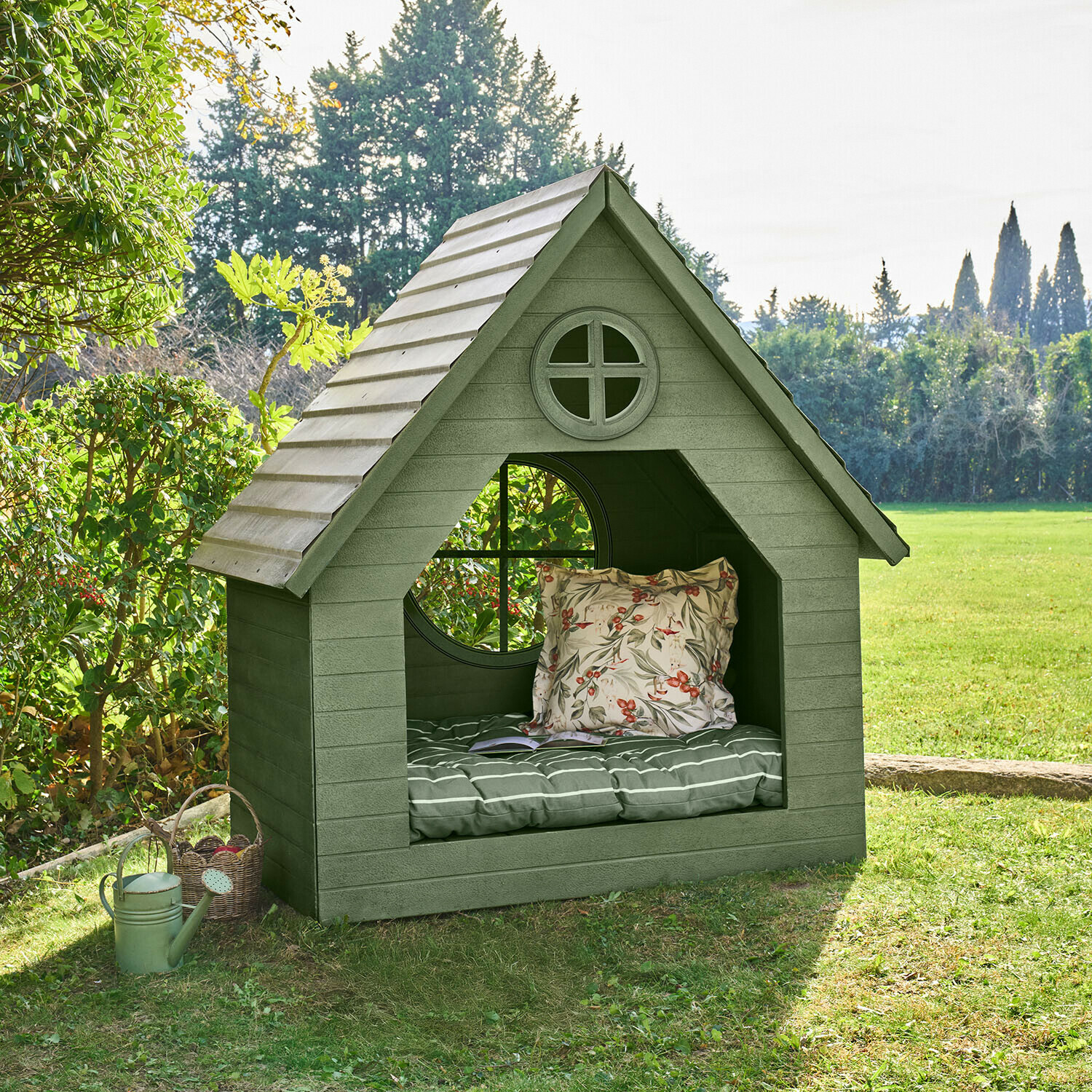 Groen houten tuinhuisje met ronde ramen en comfortabele kussens op het gras