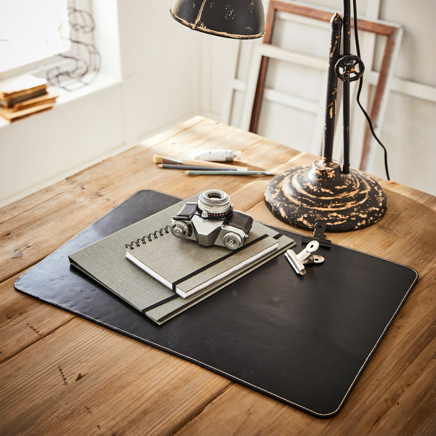 Bureaulegger Jansen Zwarte leren bureaulegger met notitieboekjes en vintage camera op lichte houten tafel