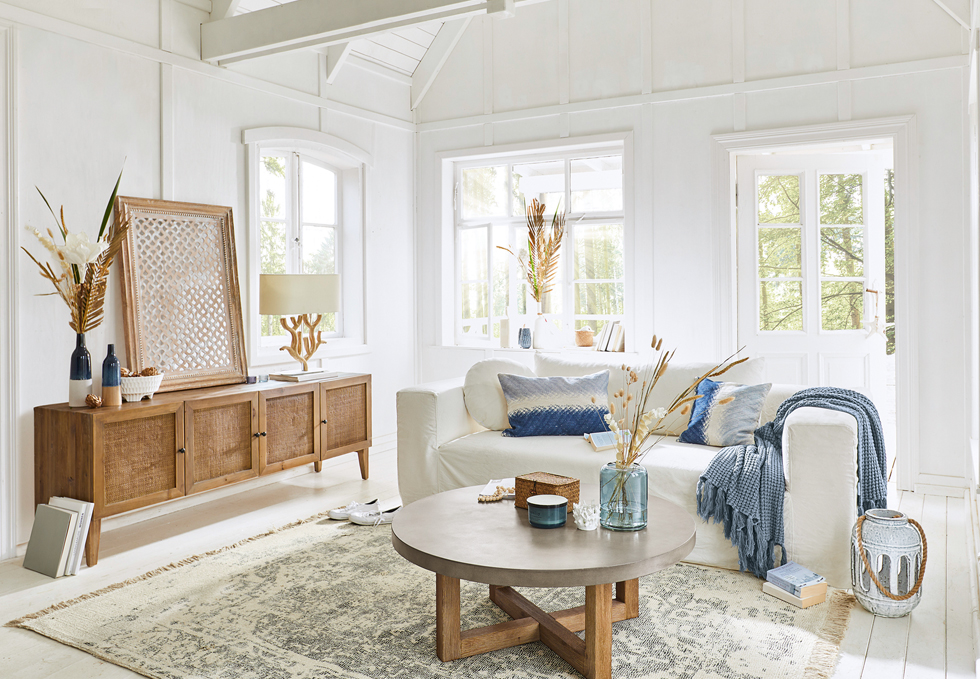 Lichte woonkamer in maritieme stijl met witte bank, houten dressoir en blauwe accenten